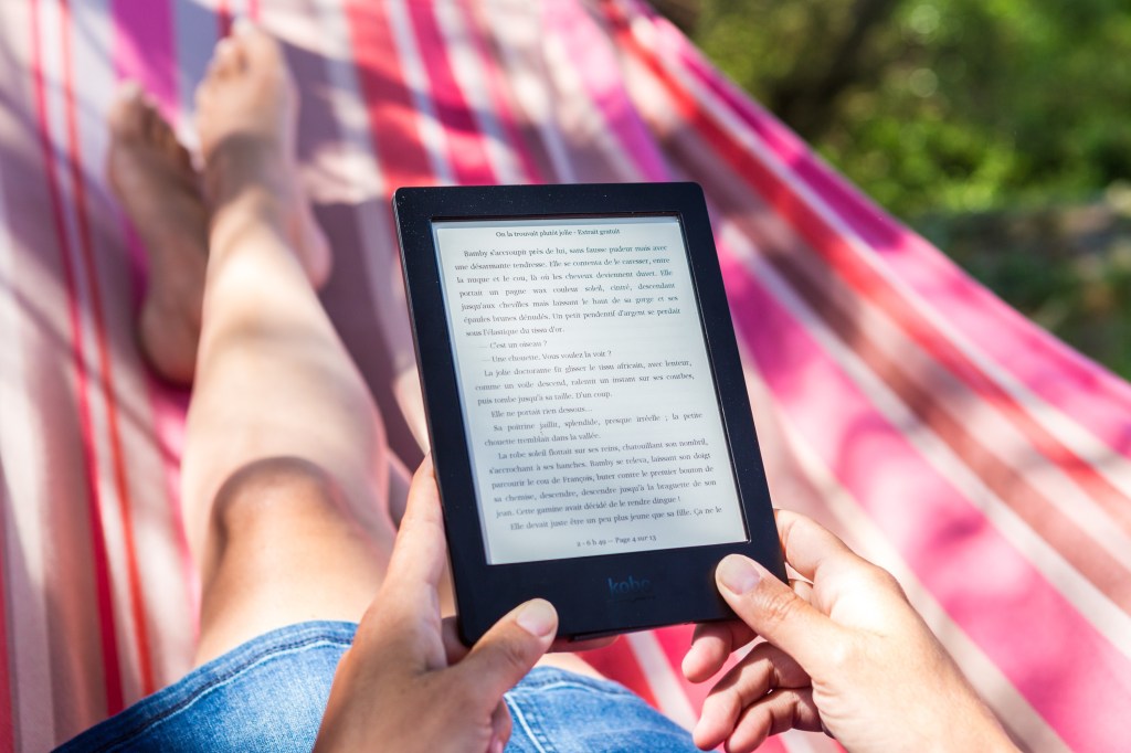 Free nonfiction for summer reading. A person in a pink and red hammock holds an e-reader in their hands.